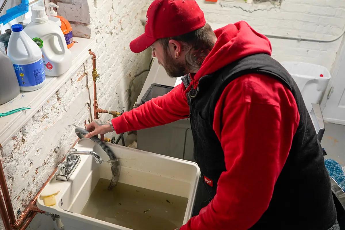 J. Blanton plumber working on the faucet of a basement utility sink