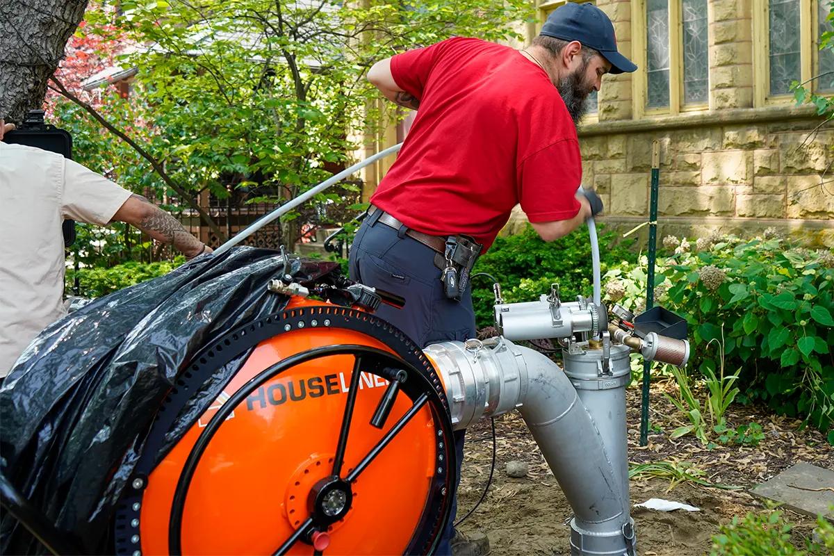 J. Blanton plumber running sewer lining equipment in a backyard