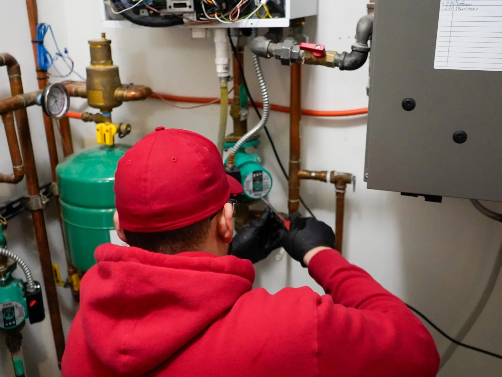 J. Blanton plumber working on the piping and circulator pumps of a commercial water heating system