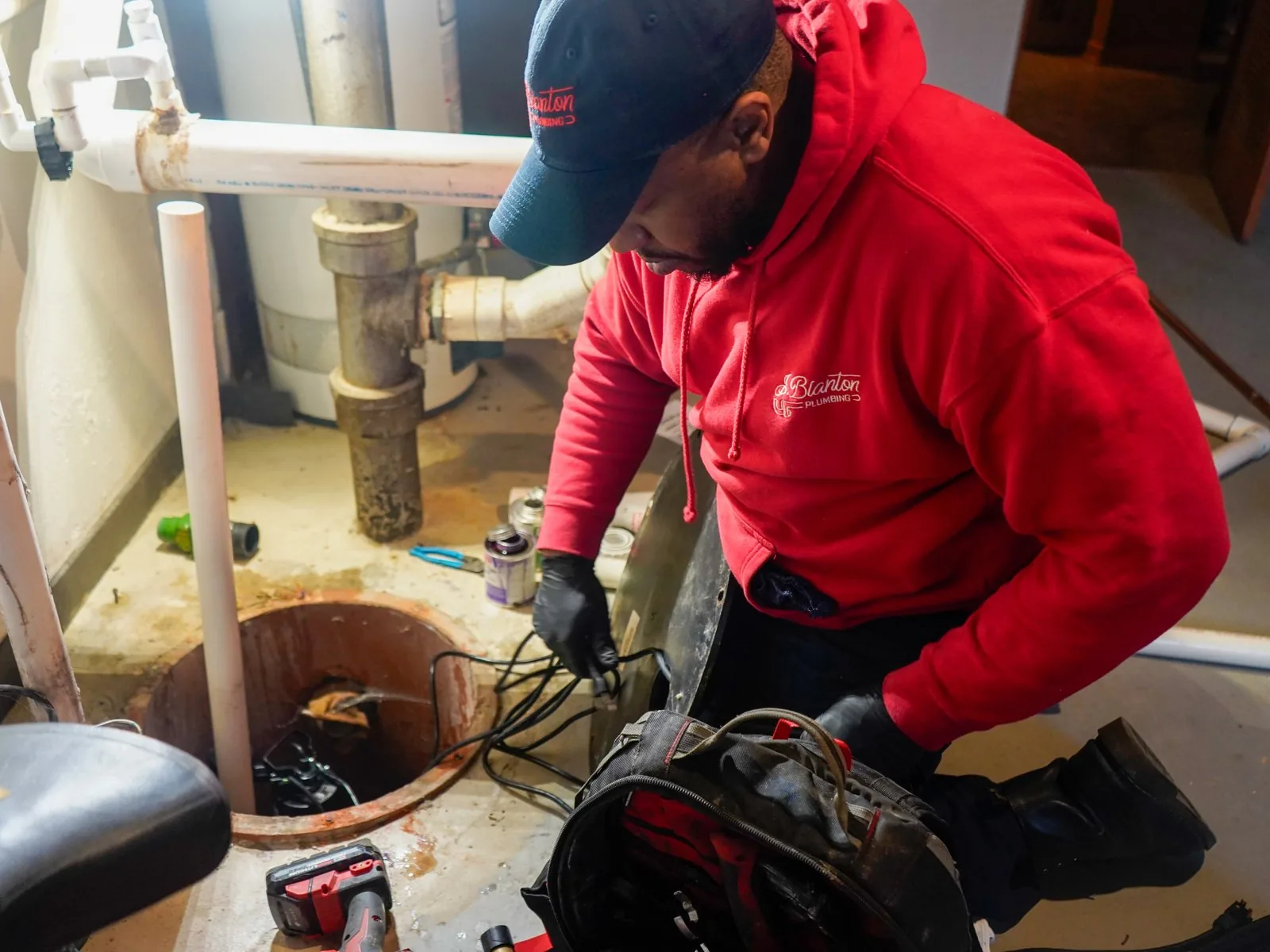 J. Blanton plumber working on the wiring of a basement sump pump pit