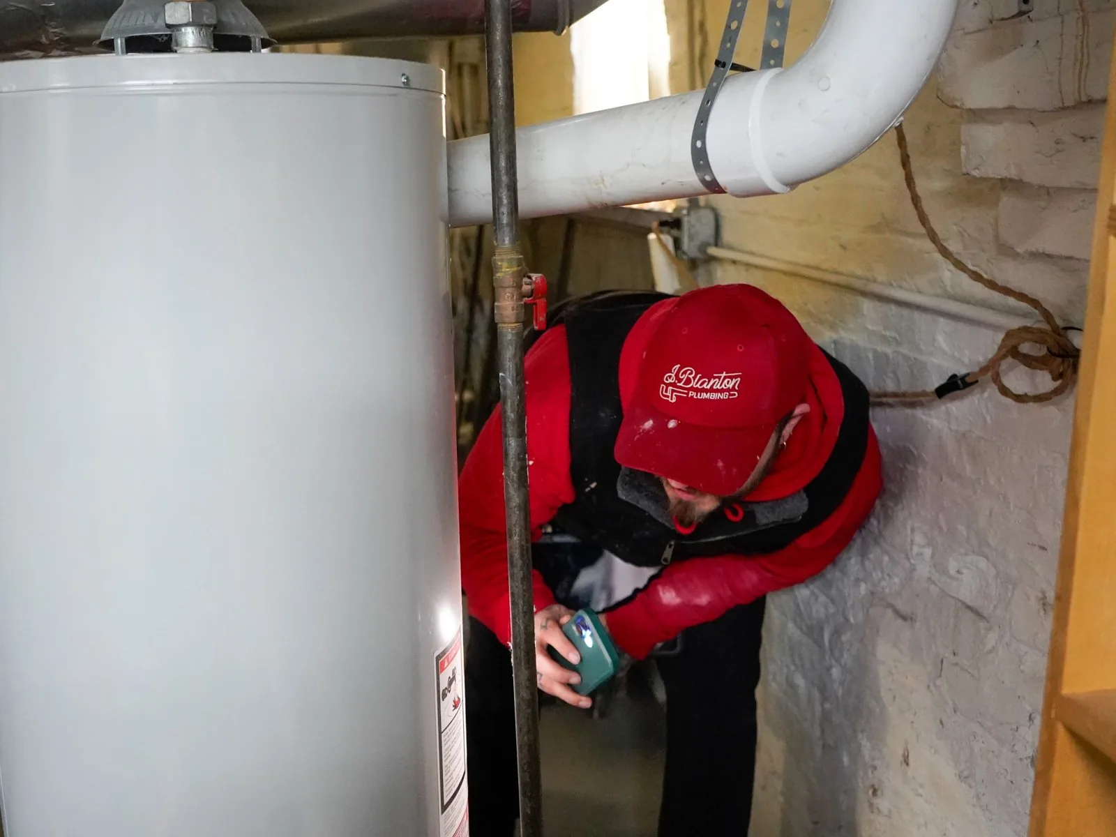 J. Blanton plumber checking the controls at the base of a basement water heater