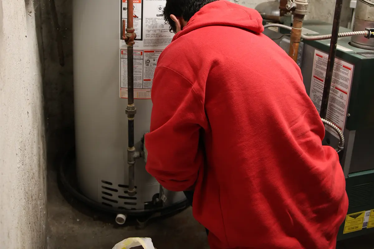 J. Blanton plumber checking a basement water heater during a maintenance visit