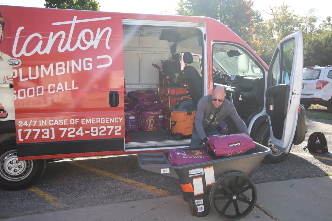 J. Blanton Plumbing team member unloading bags of dog food from a J. Blanton Plumbing van into a cart