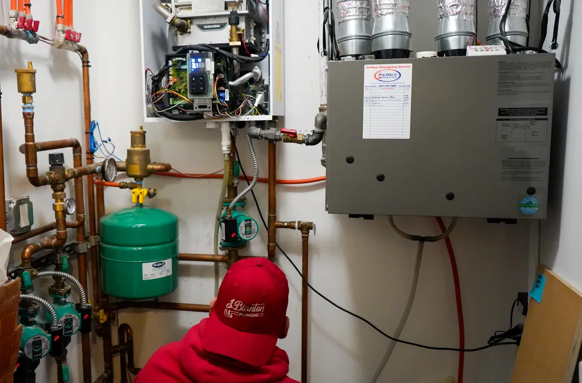 J. Blanton Plumbing technician inspecting a large tankless water heater and boiler system