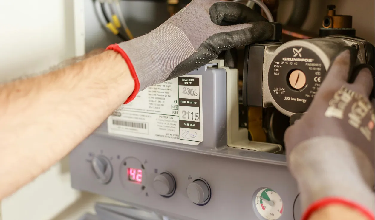 Technician in work gloves repairing the controls on a water heater