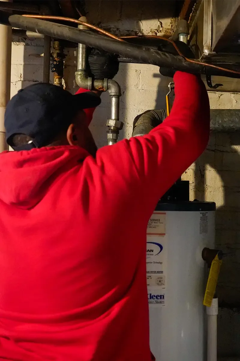 J. Blanton plumber working on the gas and vent piping above a basement water heater